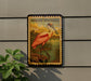 A vintage-style metal sign featuring an illustration of a pink spoonbill bird, mounted on a wall next to a plant.