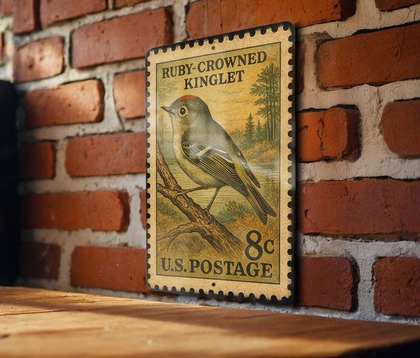A vintage postage stamp featuring a bird, specifically a Ruby-Crowned Kinglet, is displayed on a brick wall.