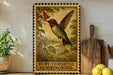 A framed illustration of a hummingbird is displayed on a shelf, with a potted plant and a wooden cutting board nearby.