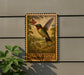 a wooden sign with a picture of a hummingbird, mounted on a wall next to a plant.