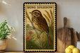A framed illustration of a brown and white bird, likely a sparrow, perched on a branch with flowers, is displayed on a shelf next to a wooden cutting board and a potted plant.