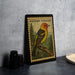 A framed stamp depicting a Western Tanager bird, a type of small songbird, is displayed on a table.
