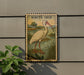a decorative stamp-like artwork depicting a white ibis bird standing in a natural setting, with a plant in the foreground.