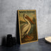 A framed illustration of a pelican, titled "WHITE PELICAN", is displayed on a wall next to a stack of black camera lenses.