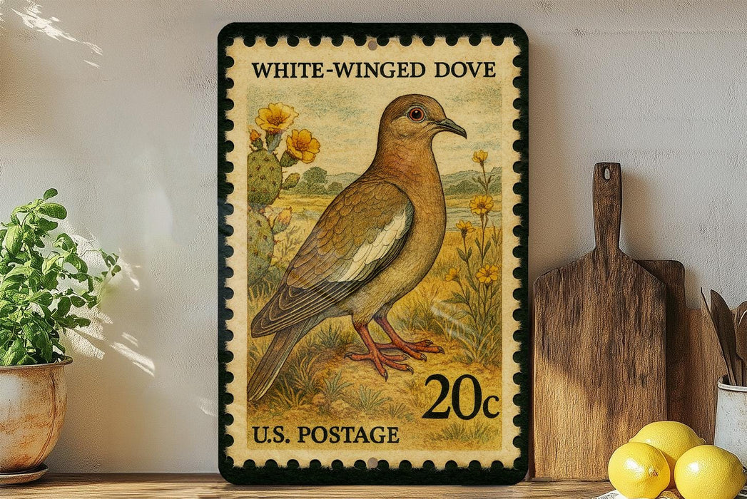 A vintage-style postage stamp depicting a white-winged dove, with a potted plant and wooden cutting board in the background.