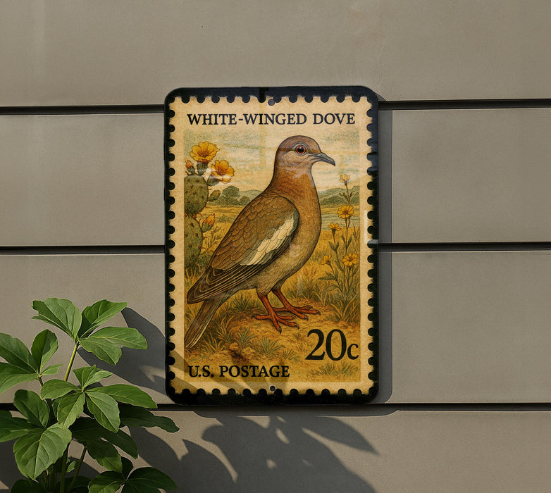 A postage stamp featuring a white-winged dove, a type of bird, is displayed on a wall.