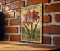 A vintage-style stamp featuring a large red flower with green leaves, mounted on a brick wall.