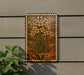 a framed painting of a flower on a wall, with a plant next to it.
