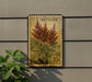 A postage stamp featuring a plant with red flowers is displayed on a wall, next to a small green plant.