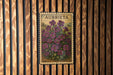 A vintage-style metal plaque with the word "AUBRIETA" printed on it, featuring a floral illustration of purple flowers.