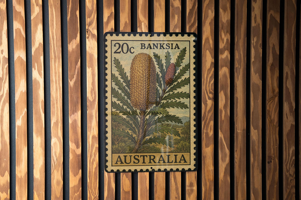 A 20c Australian postage stamp featuring a Banksia flower is displayed on a wooden wall.