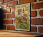 A vintage-style stamp featuring a floral illustration of red flowers, mounted on a brick wall.