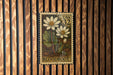A US postage stamp featuring a floral design with two white flowers and green leaves, mounted on a wooden wall.