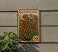 A vintage-style postage stamp featuring a floral design with red flowers and green leaves, mounted on a wall.