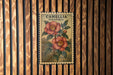 a vintage-style stamp or postcard with a floral illustration, mounted on a wooden wall.