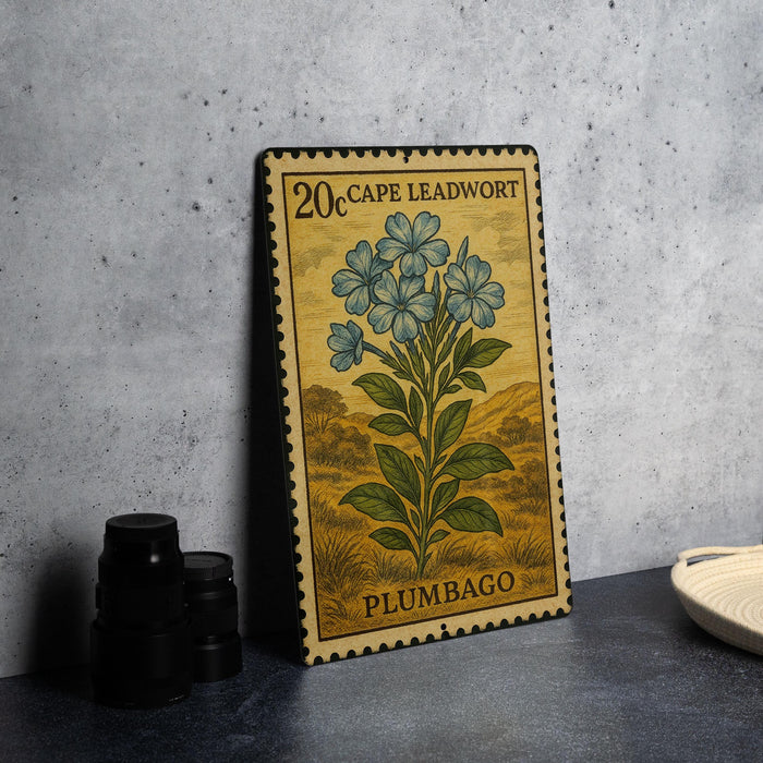 A metal stamp with a floral design and text, placed on a table next to some black camera lenses.
