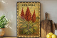 a decorative metal plate with a vibrant illustration of red flowers, placed on a wooden shelf next to a wooden cutting board and a potted plant.
