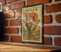 A vintage postage stamp featuring a large orange flower is displayed on a brick wall.
