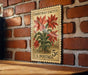 A vintage Christmas cactus postage stamp is displayed on a brick wall, with a wooden table below it.