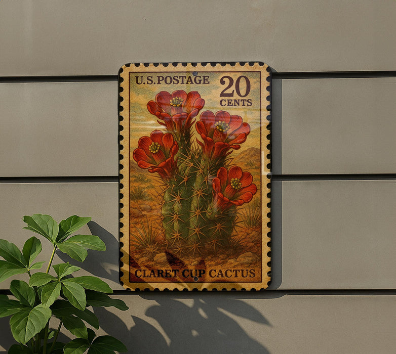 A U.S. postage stamp featuring a cactus plant with red flowers, mounted on a wall next to a plant.