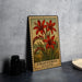 A framed illustration of red crocosmia flowers, a type of lily, is displayed on a gray wall.