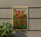 A framed illustration of crocus flowers is displayed on a wall, with a plant to the left.