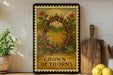 A framed poster with the text "CROWN OF THORNS" is displayed on a shelf, surrounded by various kitchen items such as a potted plant, a cutting board, and a bowl of lemons.