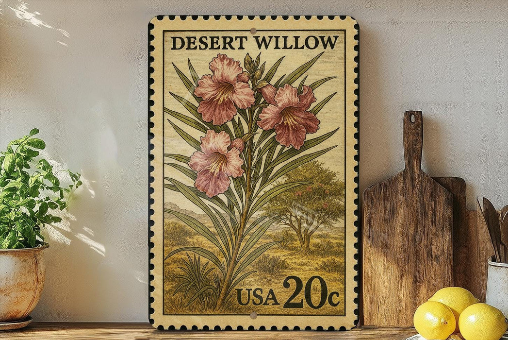 A framed vintage postage stamp featuring a floral illustration of pink flowers, placed on a wooden shelf next to a wooden cutting board and a potted plant.