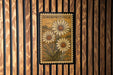 a vintage-style stamp or postcard with a floral design, hanging on a wooden wall.
