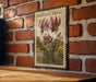 A vintage-style metal stamp depicting a purple flower with green leaves, mounted on a brick wall.