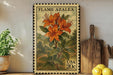 A framed image of a vibrant orange lily flower, with the text "FLAME AZALEA" and "USA 20c" printed on it, is displayed on a shelf next to a wooden cutting board and a potted plant.