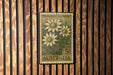 A vintage Australian postage stamp featuring a floral design is displayed on a wooden wall.