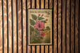 A four-clock stamp from the United States, featuring a pink flower and green leaves, is displayed on a wooden wall.