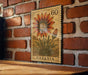 a postage stamp from Gazania, with a large sunflower depicted on it, mounted on a brick wall.