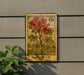 A vintage-style postage stamp featuring a vibrant illustration of a geranium plant, mounted on a wall next to a potted plant.