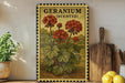 A framed illustration of geranium flowers is displayed on a shelf, accompanied by a wooden cutting board and a potted plant.