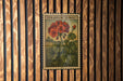 A vintage-style metal stamp featuring a geranium plant with red flowers and green leaves, mounted on a wooden wall.