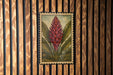 a vibrant red flower with green leaves, set against a wooden background with vertical slats.