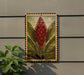 a framed illustration of a red flower with green leaves, hanging on a wall next to a plant.