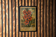 A framed image of a flower, specifically Gladiolus, is displayed on a wooden wall.