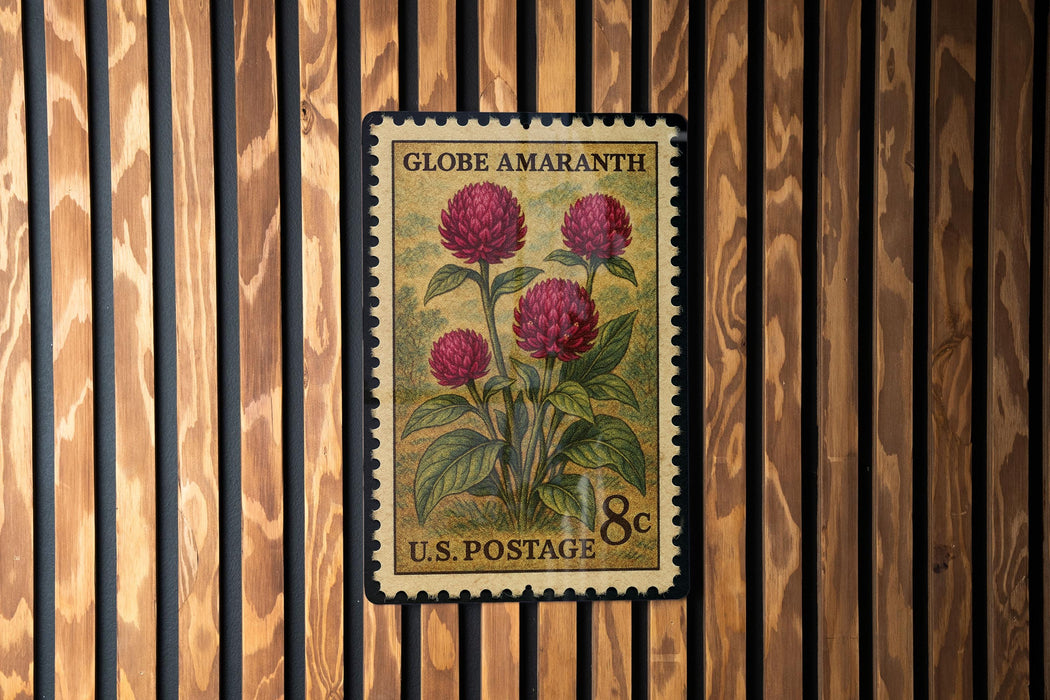 A vintage U.S. postage stamp featuring a floral design with three red flowers, mounted on a wooden wall.