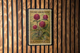 A vintage U.S. postage stamp featuring a floral design with three red flowers, mounted on a wooden wall.