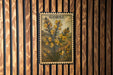 a framed illustration of a plant with yellow flowers, mounted on a wooden wall.