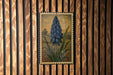 a framed painting of a blue flower on a wooden wall.