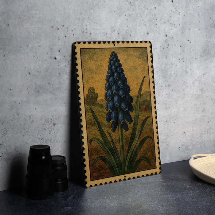 a framed illustration of a blue flower on a table, with a stack of black camera lenses and a white plate visible in the background.
