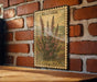 A framed illustration of a plant with pink flowers is displayed on a brick wall, with the word "HEATHER" and "CALLLuna" printed on the frame.