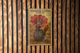 A vintage-style postage stamp featuring a detailed illustration of a red-flowered hedgehog cactus flower is displayed on a wooden wall.