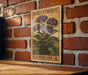 A vintage U.S. postage stamp featuring a purple heliotrope plant is displayed on a brick wall.