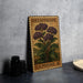 A vintage Heliotrope postage stamp featuring a plant illustration, placed on a gray countertop next to some black camera lenses.