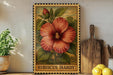 A framed illustration of a red hibiscus flower is displayed on a shelf, accompanied by a wooden cutting board, a potted plant, and a bowl of lemons.